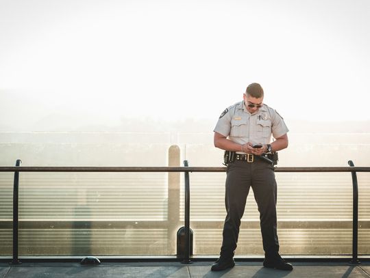 cop leaning on metal rail during a sunny day